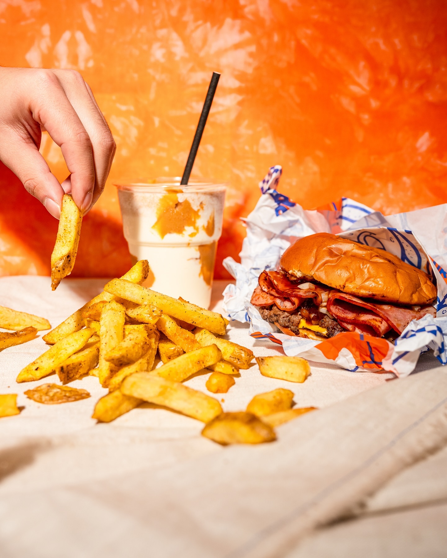 A plate of golden fries and a burger with layers of bacon and cheese at Drippy's, a halal restaurant in Rotterdam, Netherlands.