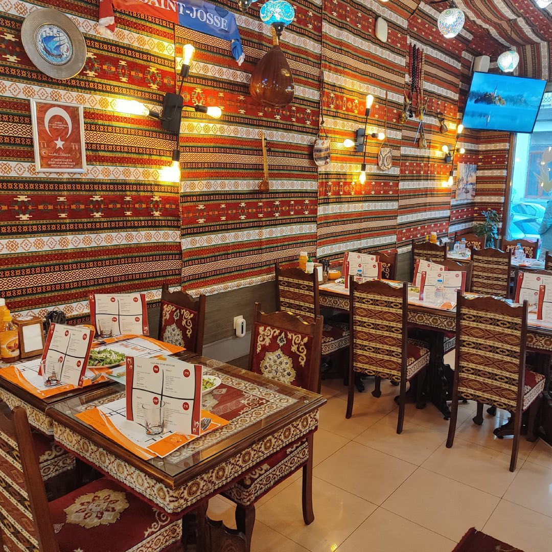 The interior of halal restaurant Lale in Schaerbeek, Belgium, showing patterned walls, wooden tables, and chairs with decorative upholstery.