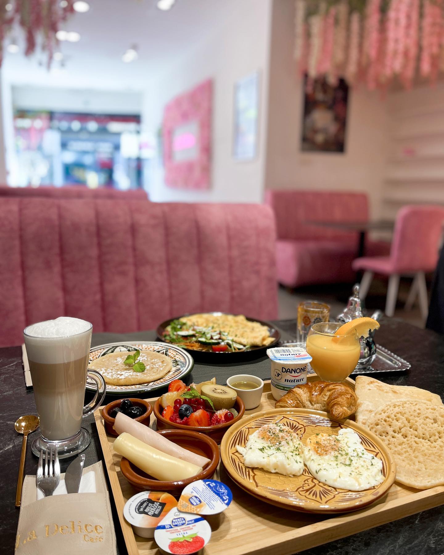 A breakfast platter at La Delicé Café, a halal restaurant in Mechelen, Belgium, featuring eggs, fruits, pastries, and beverages.