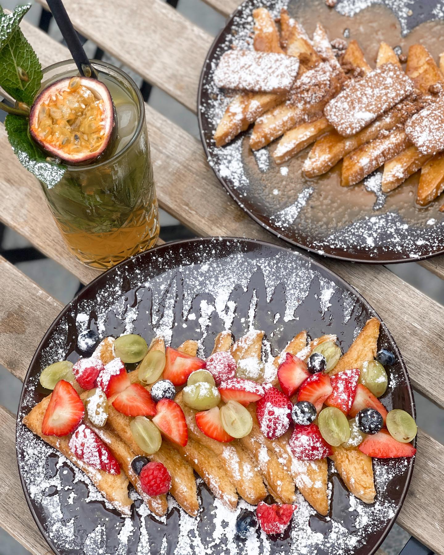 A plate of sweet pastries topped with powdered sugar and fresh fruits, served at La Delicé Café, a halal restaurant in Mechelen, Belgium.