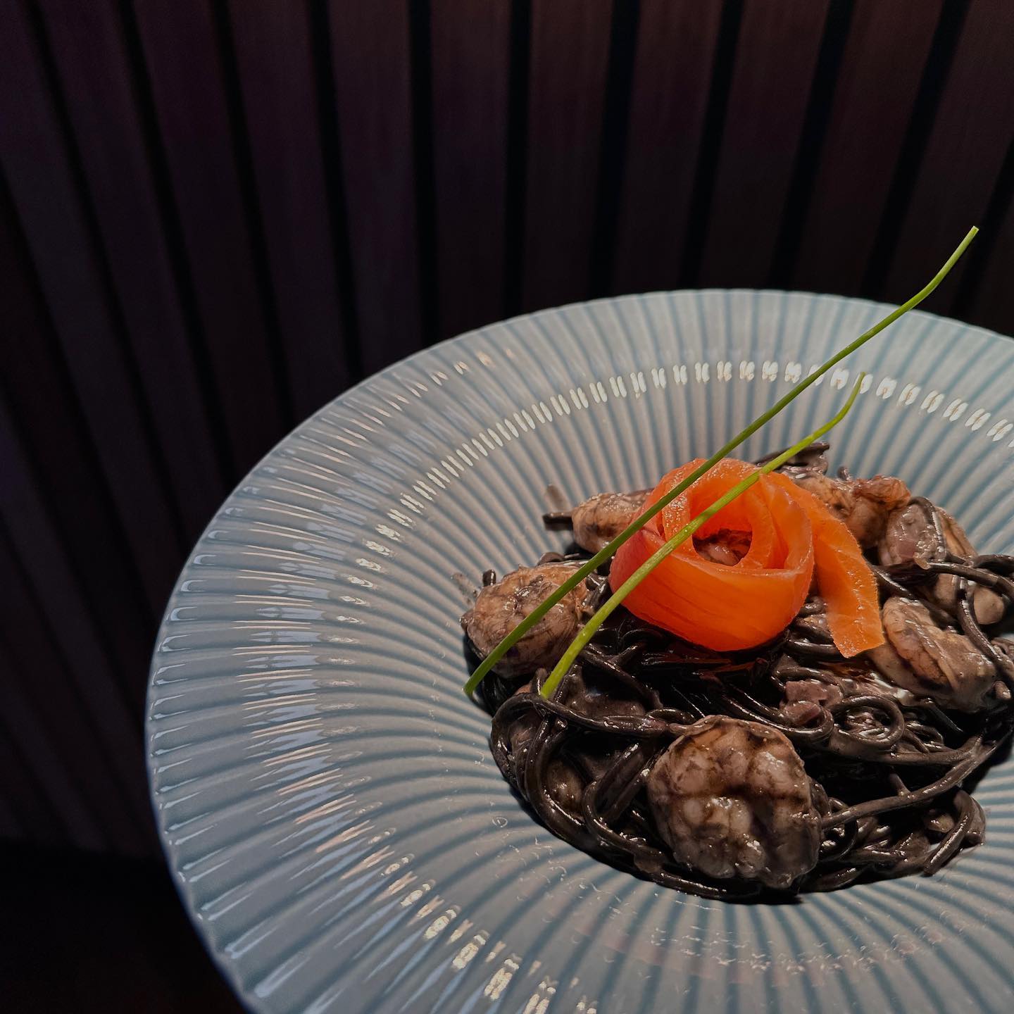A plate of black spaghetti with shrimp and a garnish of carrot at GIA Restaurant, a halal restaurant in Amsterdam, Netherlands.