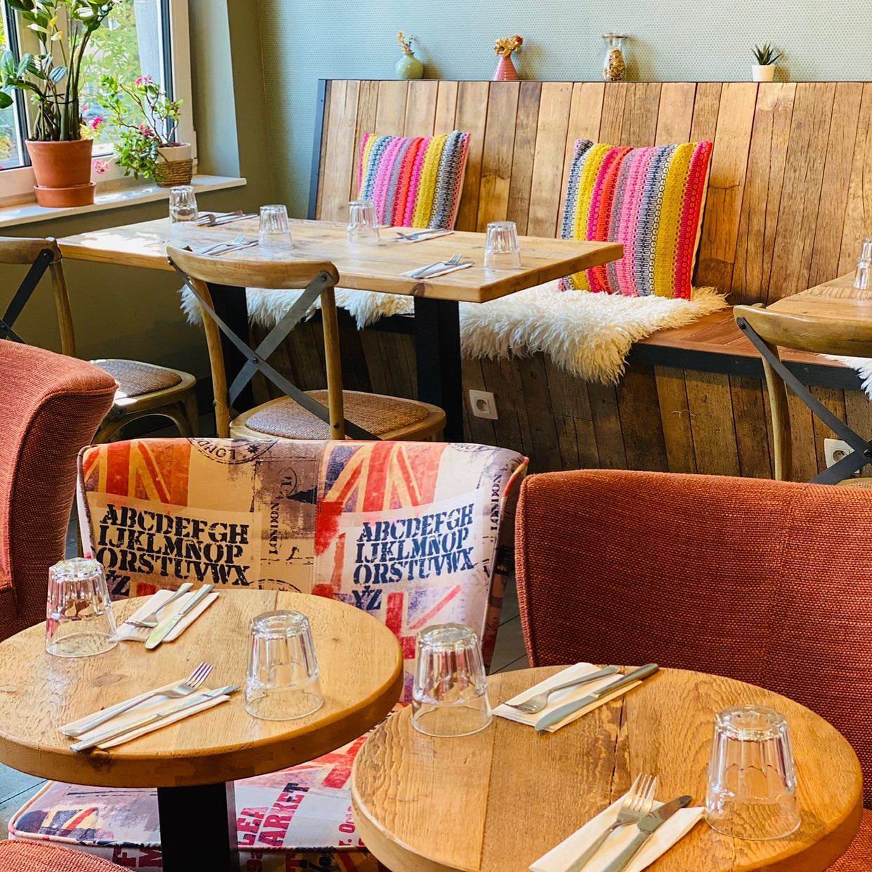 The interior of halal restaurant La Table Rustique in Bruxelles, Belgium, showing wooden tables, colorful cushions, and a cozy seating area with plants.