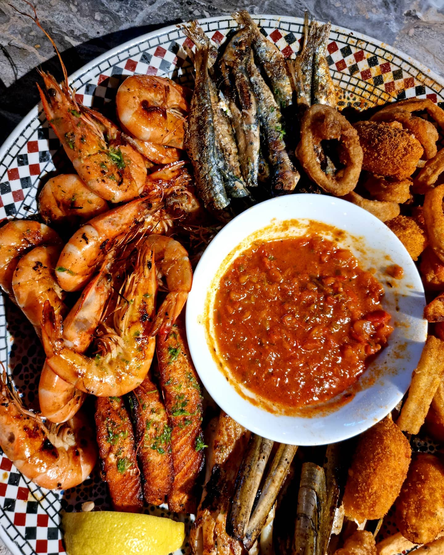A seafood platter featuring grilled shrimp, small fish, calamari, and a spicy dipping sauce at Zeester Eindhoven, a halal restaurant in Eindhoven, Netherlands.