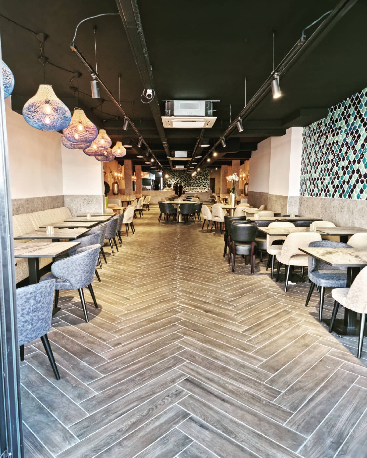 The interior of halal restaurant Zeester Eindhoven in Eindhoven, Netherlands, showing a spacious dining area with modern furniture, decorative lighting, and a patterned wall.