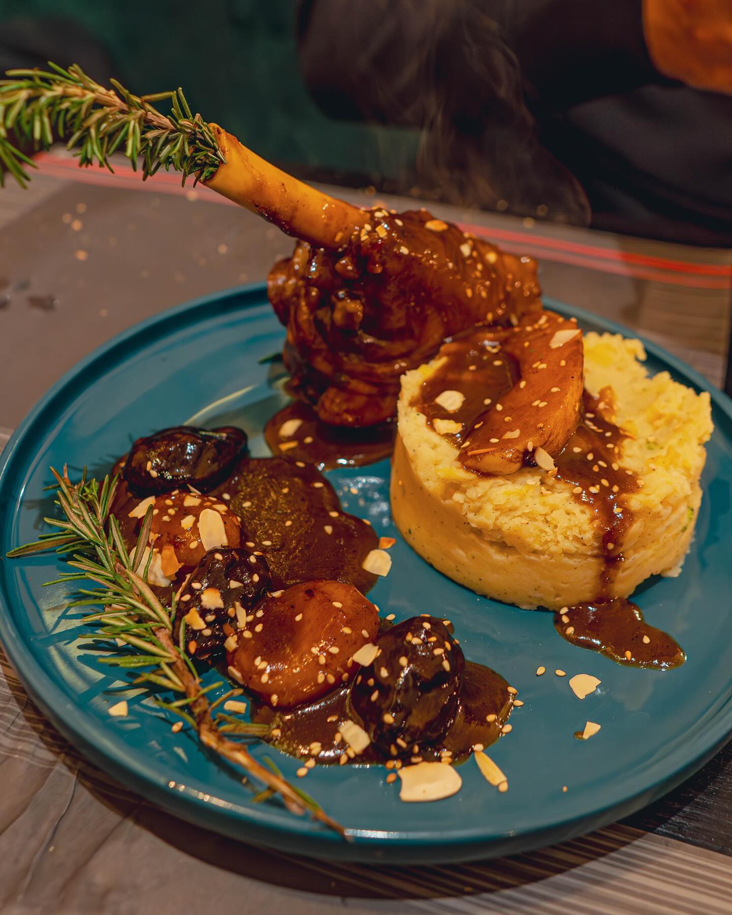 Een bord met lamsbout met aardappelpuree en een rijke saus, gegarneerd met rozemarijn, bij Wyngs, een halal restaurant in Schaerbeek, België.