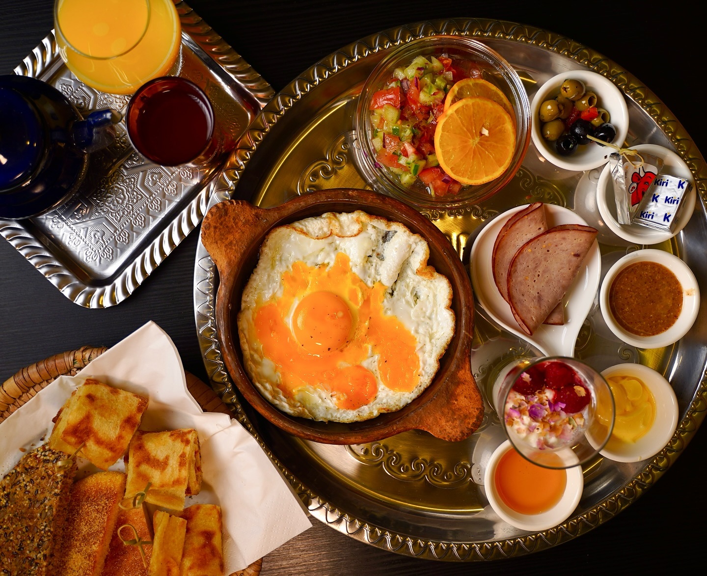 Een traditioneel Turks ontbijt bij Wyngs, een halal restaurant in Schaerbeek, België, met gebakken eieren, olijven, gesneden vleeswaren, verse groenten en verschillende dips, geserveerd met brood en dranken.