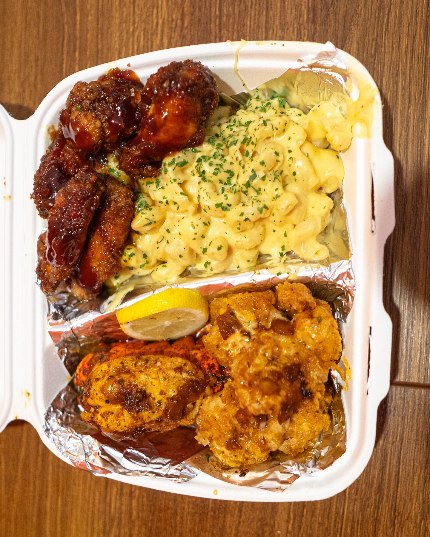 Une portion de ailes de poulet frites avec sauce barbecue, macaroni au fromage et crevettes frites au Traphouse Food, un restaurant halal à Bruxelles, Belgique.