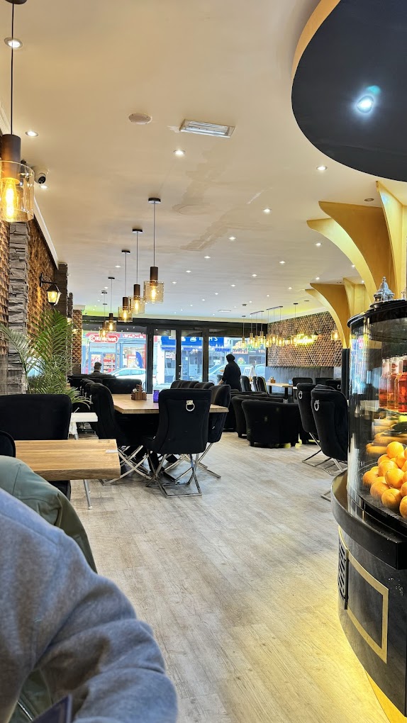 L'intérieur du restaurant halal The Room à Anvers, en Belgique, montrant une décoration moderne, des tables en bois, des chaises noires et de grandes fenêtres donnant sur la rue.