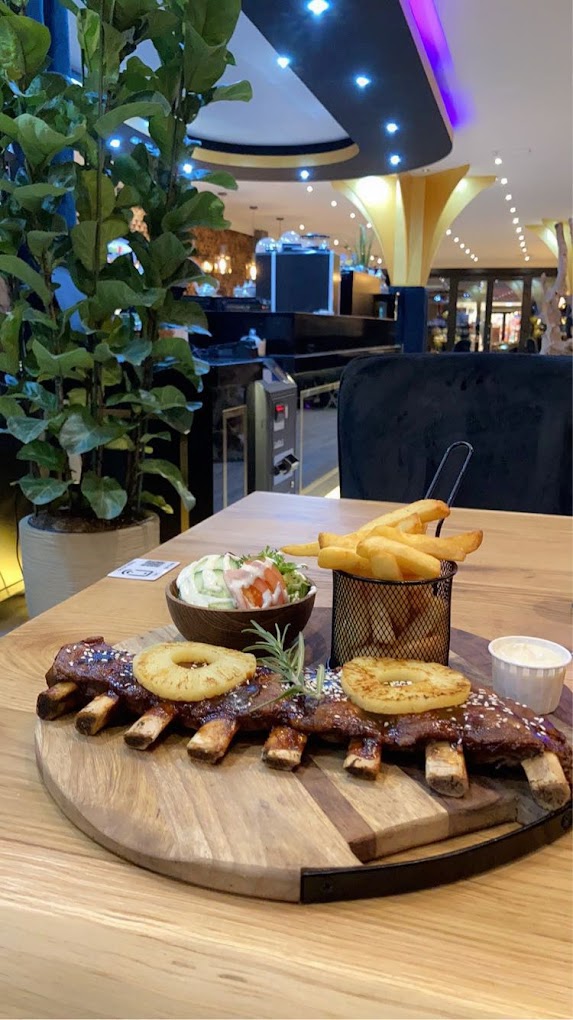 Une assiette de côtes grillées avec ananas, frites et salade au restaurant halal The Room à Anvers, Belgique.