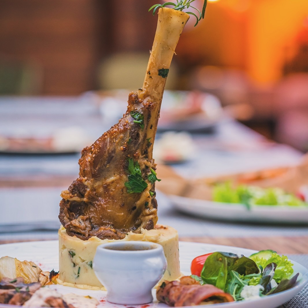A roasted lamb shank served with mashed potatoes and a small bowl of sauce at O'Tweat, a halal restaurant in Jette, Belgium.