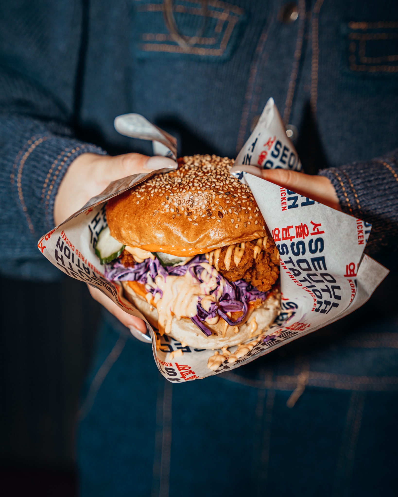 A sesame seed chicken burger with purple cabbage and sauce at Seoul South Station, a halal restaurant in Leuven, Belgium.