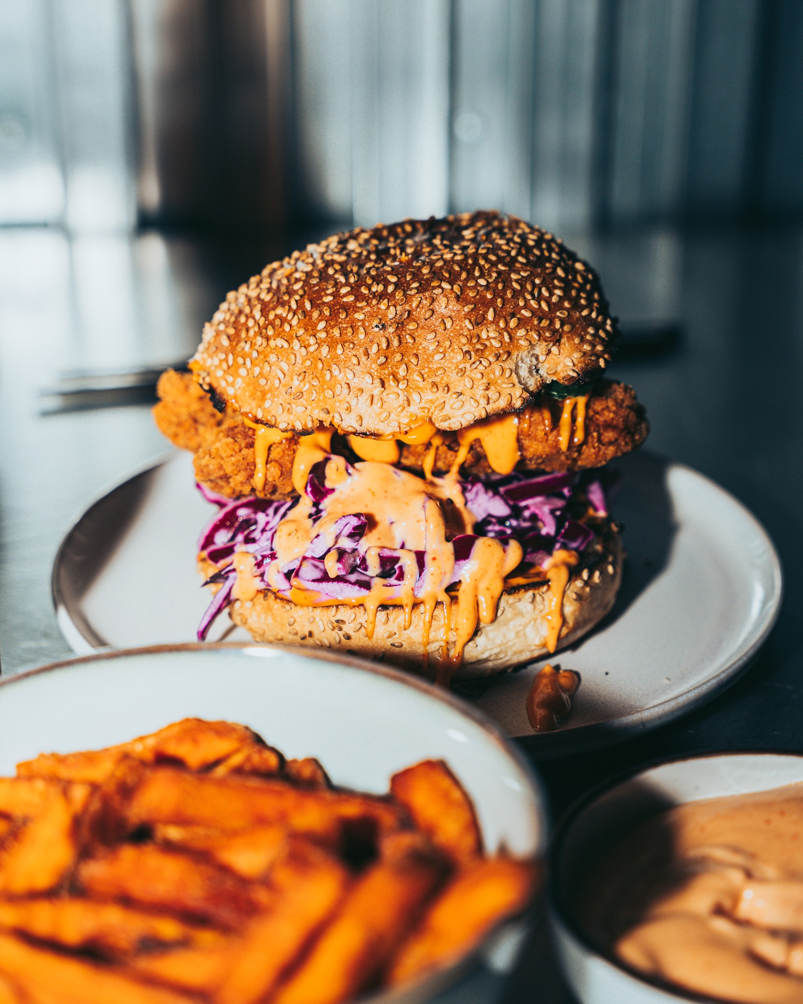 A sesame seed bun filled with fried chicken, purple cabbage, and a spicy sauce at Seoul South Station, a halal restaurant in Leuven, Belgium.