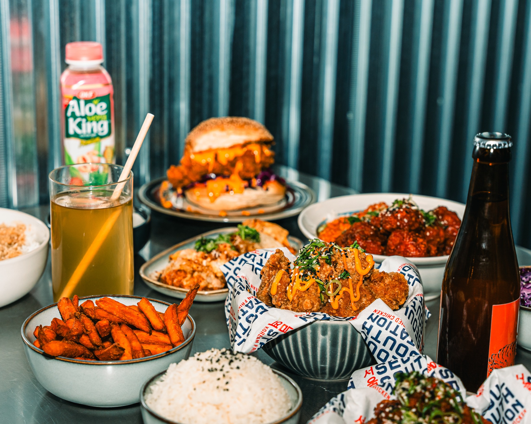 A variety of halal dishes including fried chicken, sweet potato fries, rice, and drinks at Seoul South Station, a halal restaurant in Leuven, Belgium.