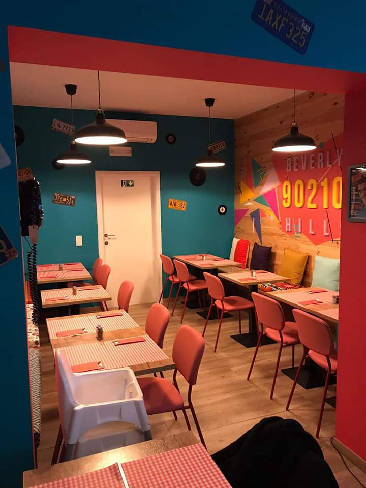 L'intérieur du restaurant halal Peach Pit à Schaerbeek, Belgique, montrant des murs colorés, des accents en bois et des tables dressées avec des nappes à carreaux.