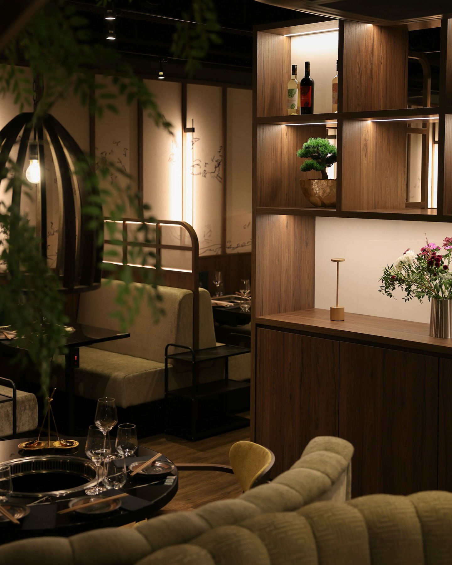 The interior of halal restaurant Sorae in Eindhoven, Netherlands, showing wooden shelves with bottles, a cozy seating area, and decorative plants.