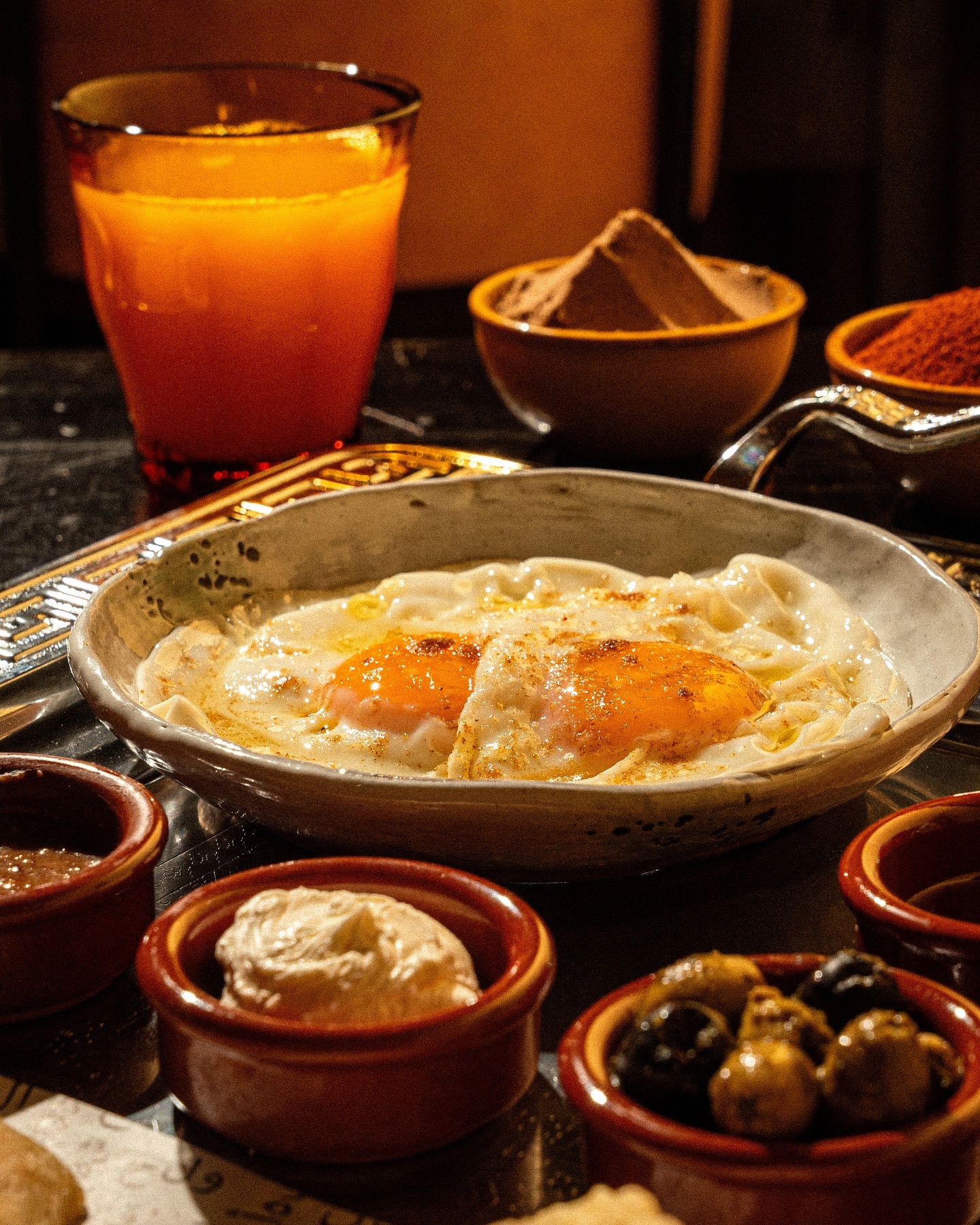 A plate of eggs with runny yolks served with various dips and olives at Lella, a halal restaurant in Antwerpen, Belgium.