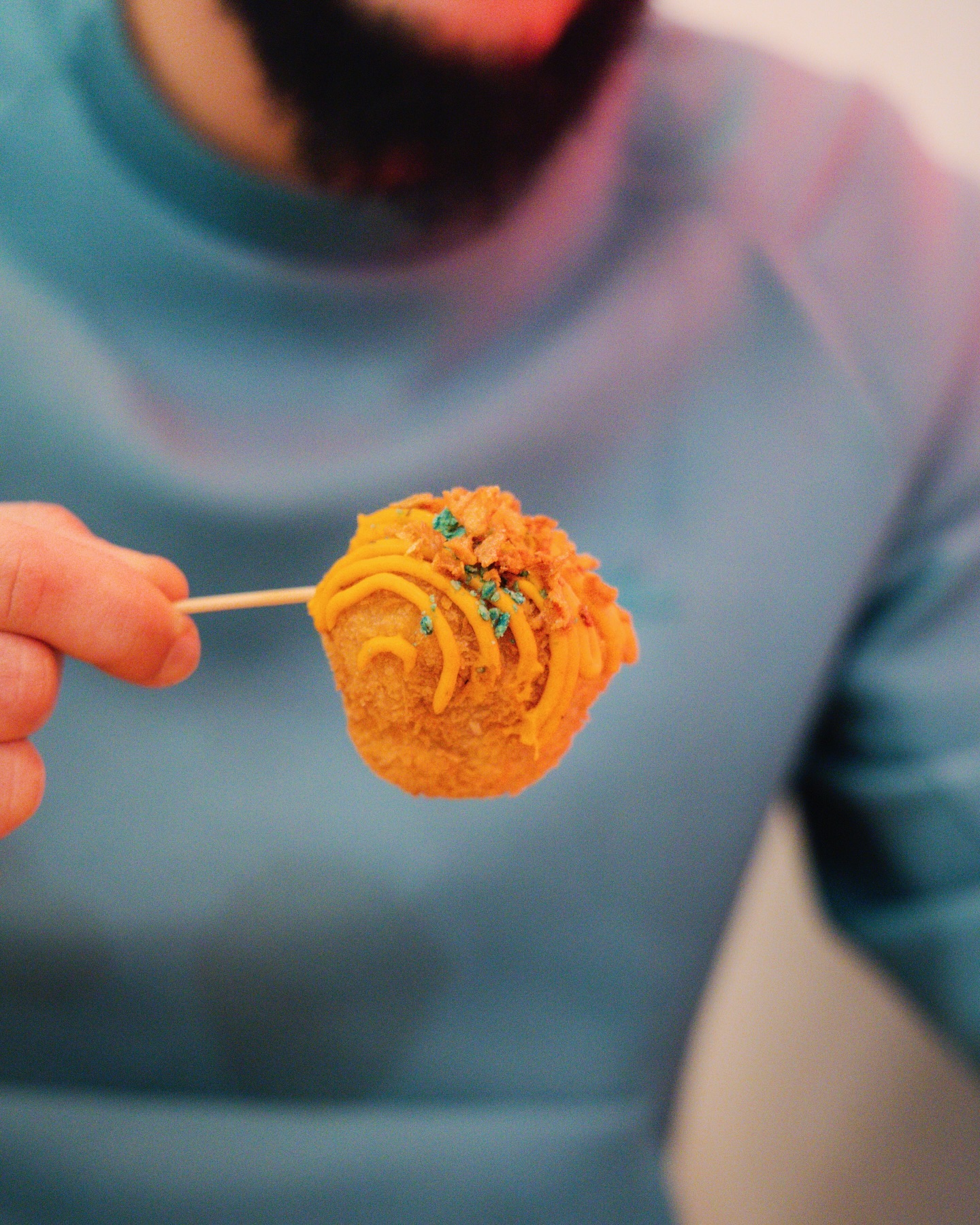 A corndog with orange frosting and sprinkles at Sekaï Corndogs, a halal restaurant in Bruxelles, Belgium.