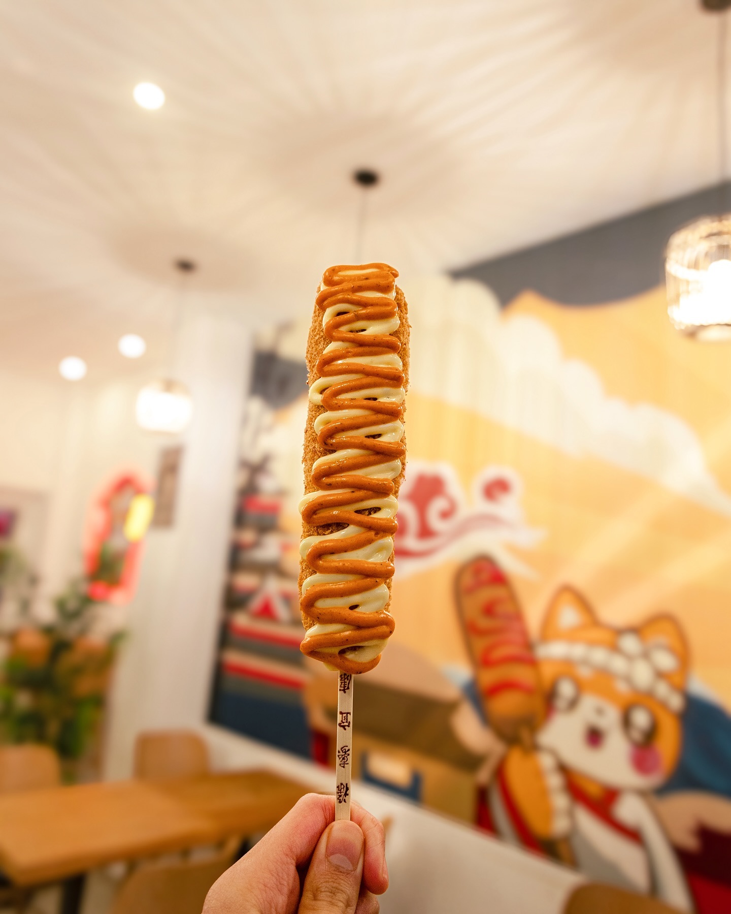 A corndog drizzled with peanut butter and chocolate sauce at Sekaï Corndogs, a halal restaurant in Bruxelles, Belgium.
