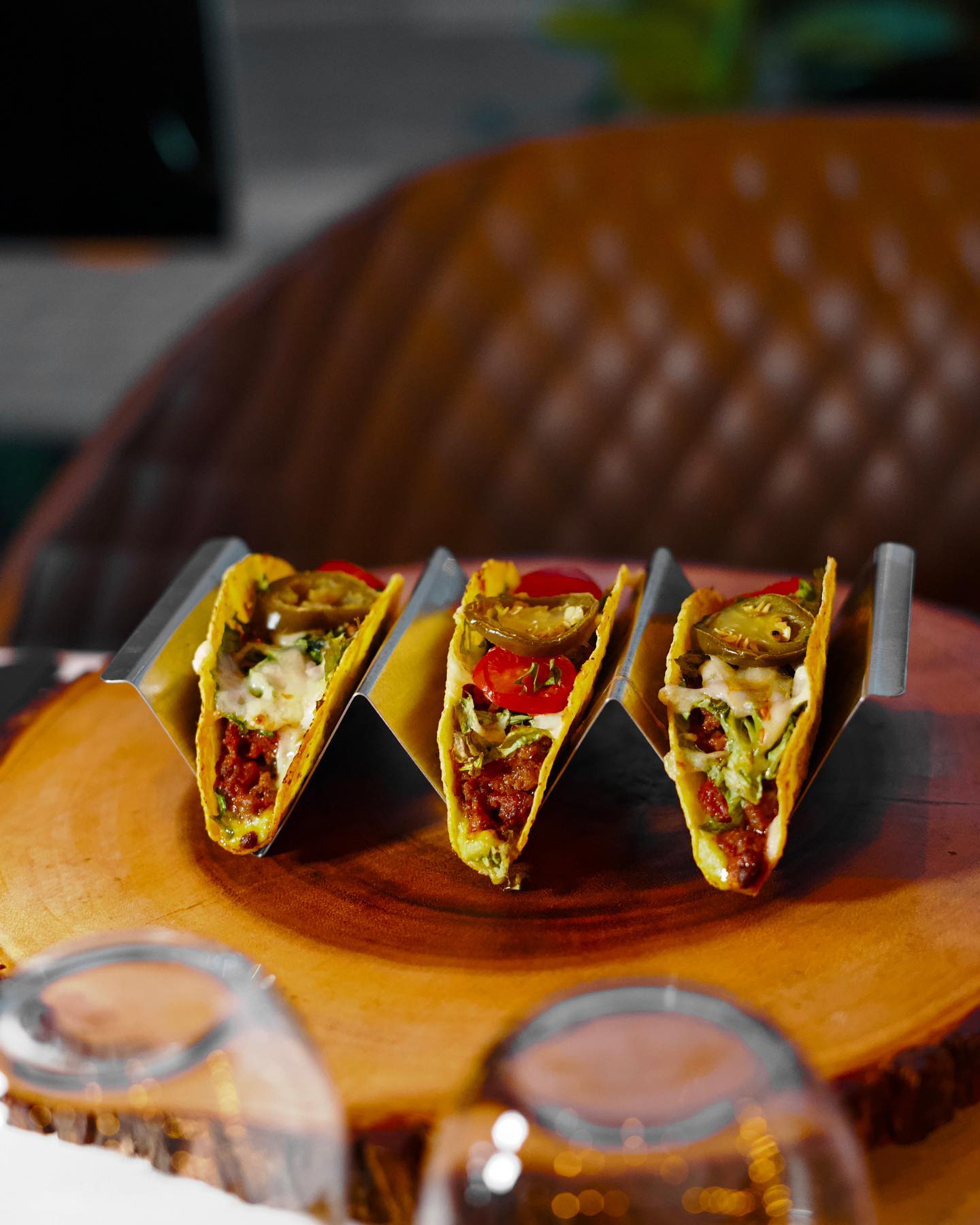 A plate of three tacos filled with meat, topped with lettuce, tomatoes, jalapeños, and sauce at La Ruche, a halal restaurant in Bruxelles, Belgium.