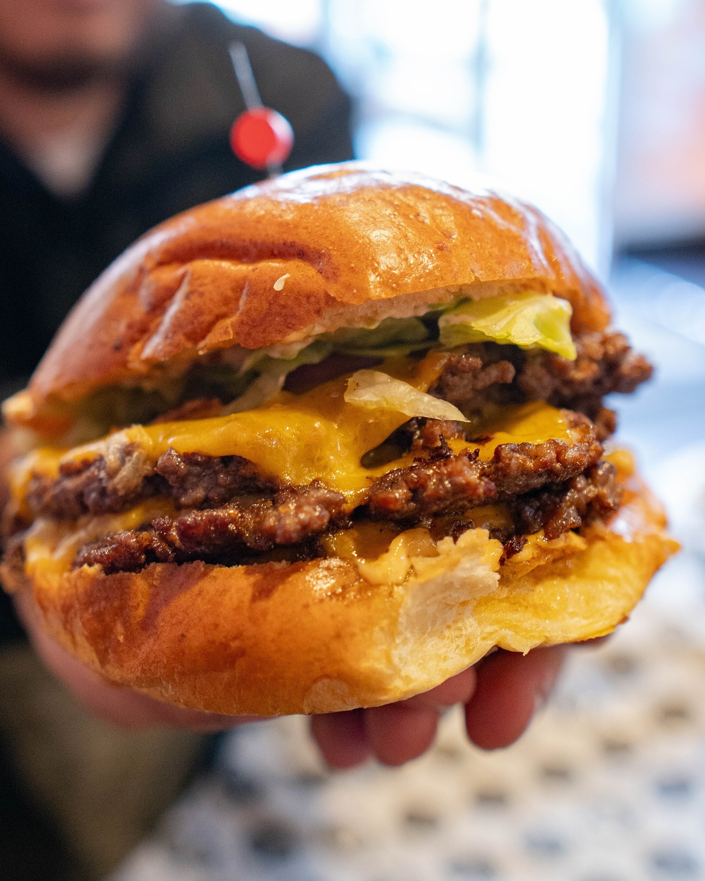 A cheeseburger with two beef patties, cheddar cheese, lettuce, and a cherry on top at Food Korner, a halal restaurant in Anderlecht, Belgium.