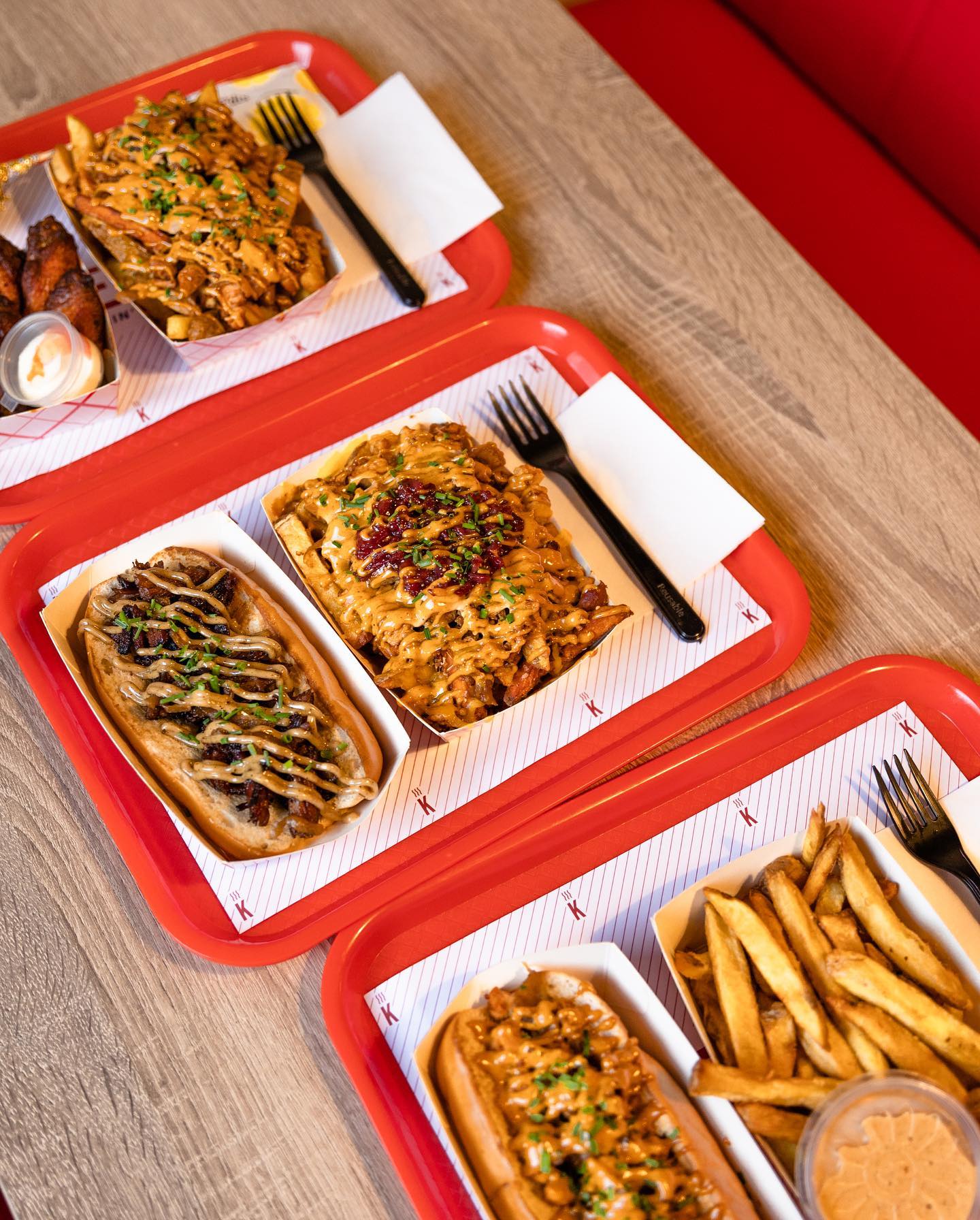 A variety of halal dishes including loaded fries, a hot dog topped with meat and sauce, and chicken wings at De Kiet, a halal restaurant in Eindhoven, Netherlands.