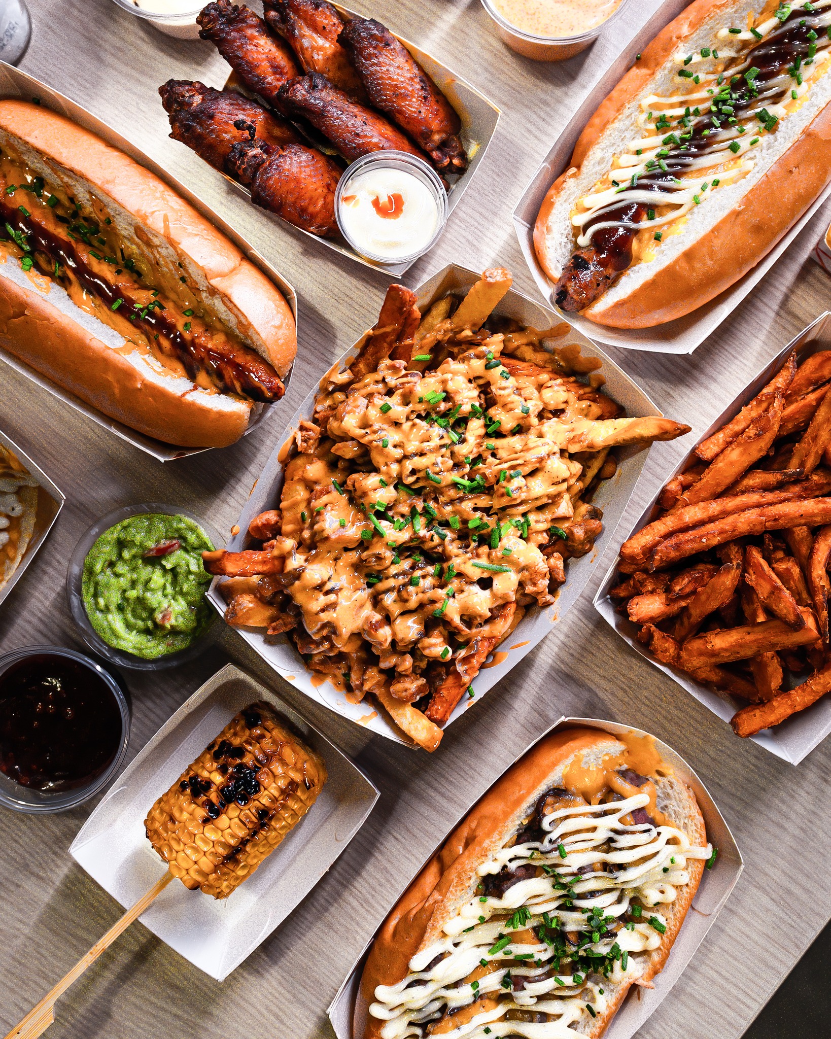 A variety of halal dishes including hot dogs, chicken wings, loaded fries, sweet potato fries, and grilled corn at De Kiet, a halal restaurant in Eindhoven, Netherlands.