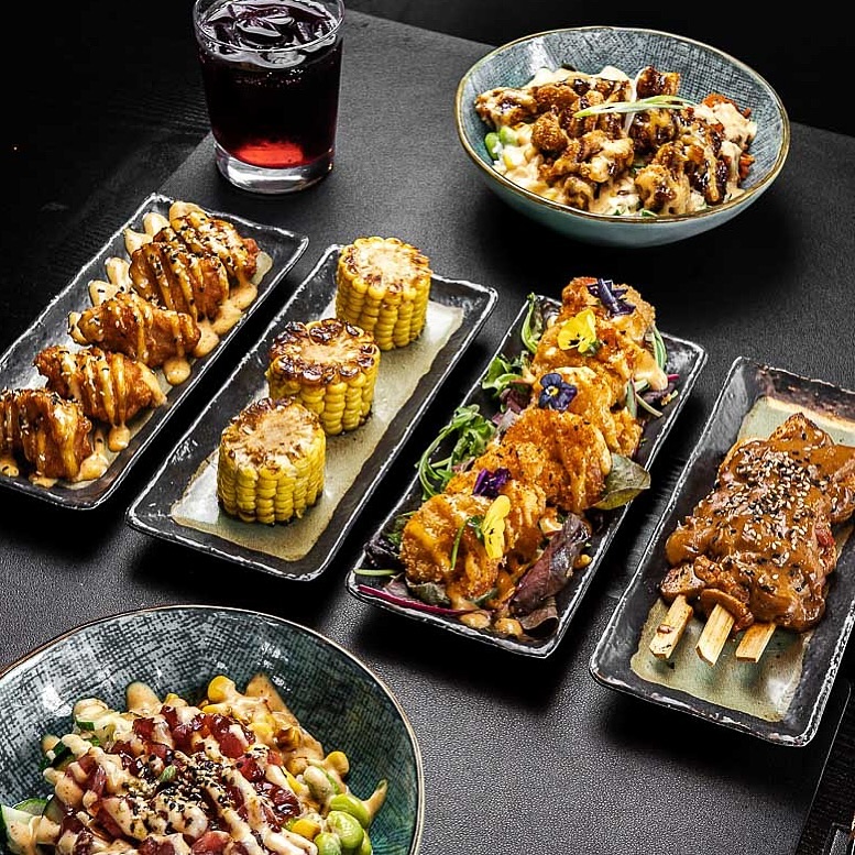 A variety of grilled and fried dishes including corn, chicken skewers, and a salad at La Vida, a halal restaurant in Utrecht, Netherlands.