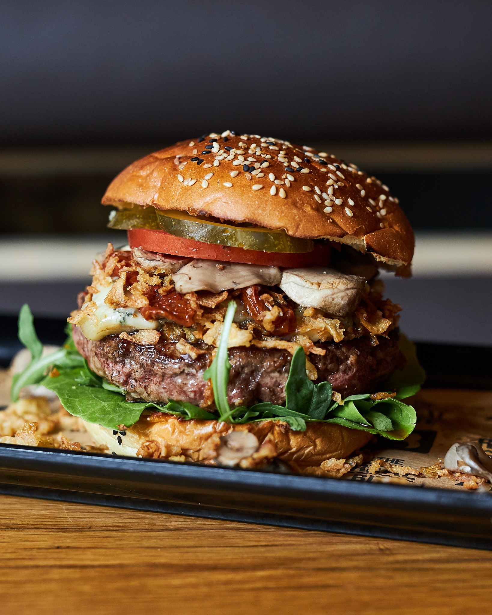 Een burger met een sesambroodje, sla, tomaat, augurken, champignons en krokante uien bij Burger Bar, een halal restaurant in Amsterdam, Nederland.