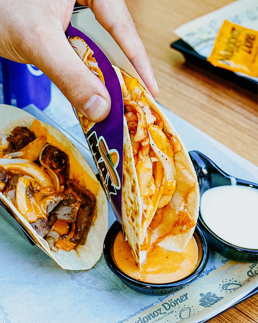 A hand holding a taco filled with chicken and sauce at Maydonoz, a halal restaurant in Den Haag, Netherlands.