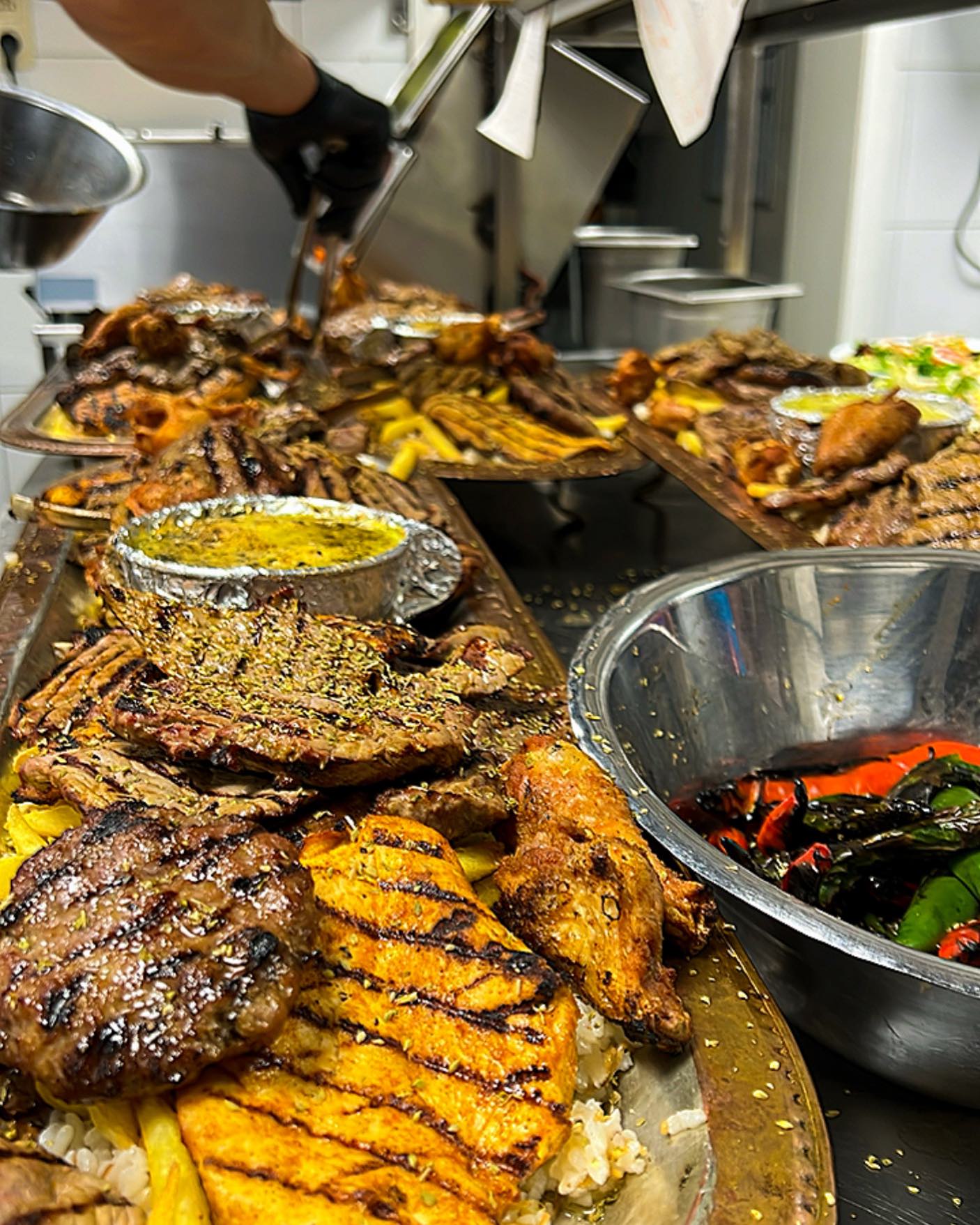A platter of grilled meats including chicken, beef, and lamb, served with rice and vegetables at Konak Steakhouse, a halal restaurant in Destelbergen, Belgium.