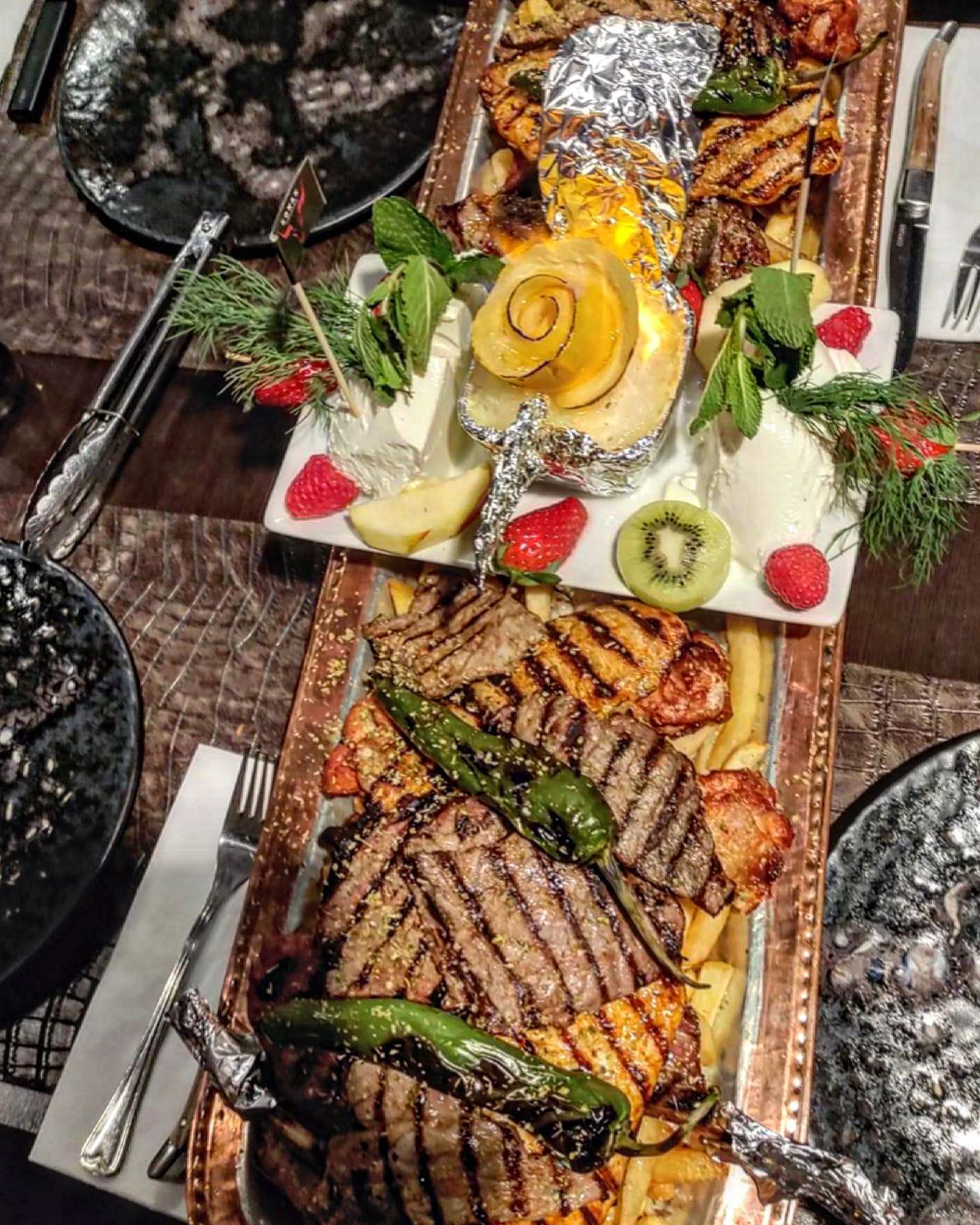 A platter of grilled meats, including beef and chicken, served with vegetables and garnished with herbs at Konak Steakhouse, a halal restaurant in Destelbergen, Belgium.