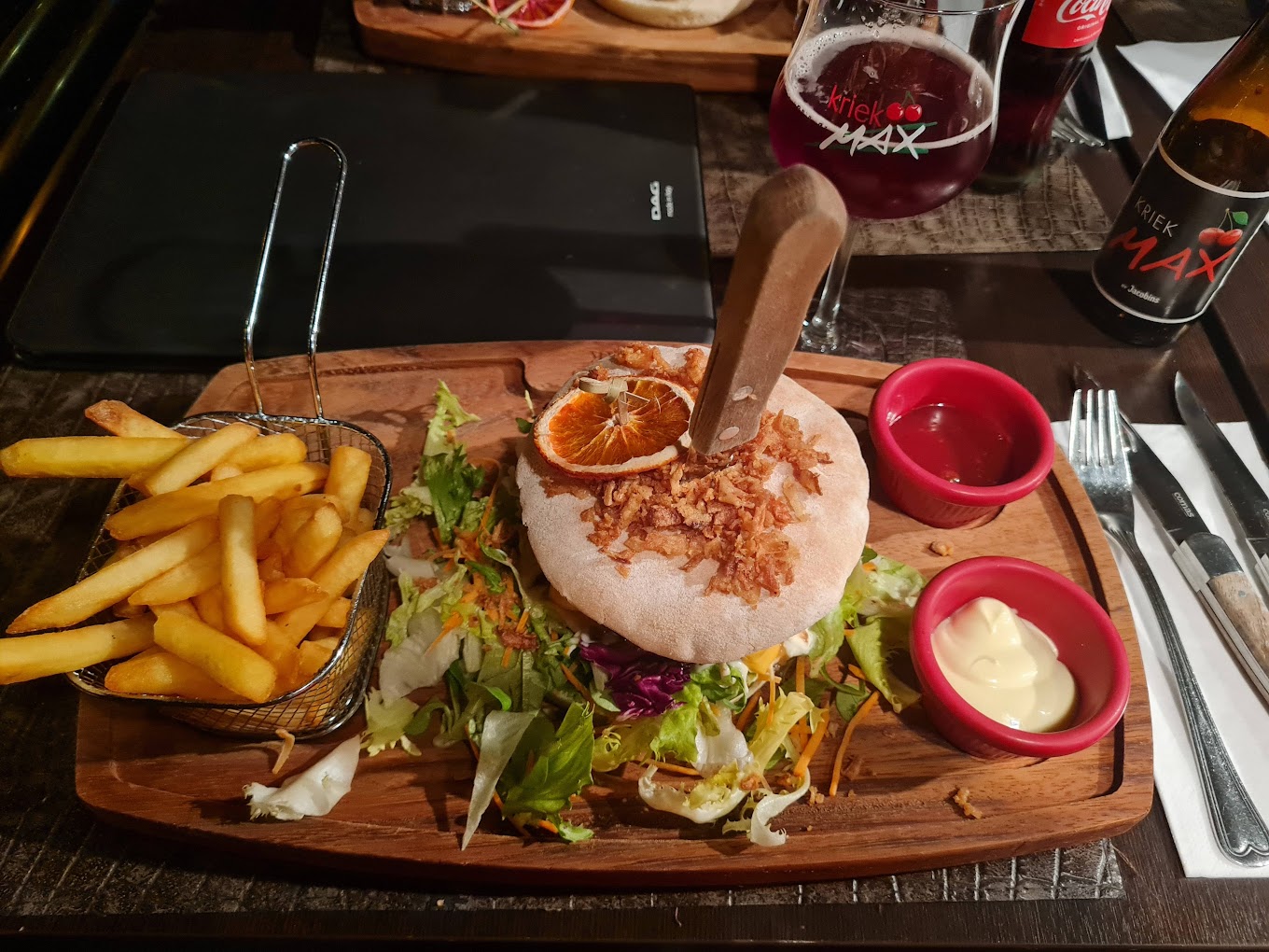 A plate of a burger with fried onions, served with a side of French fries and salad at Konak Steakhouse, a halal restaurant in Destelbergen, Belgium.