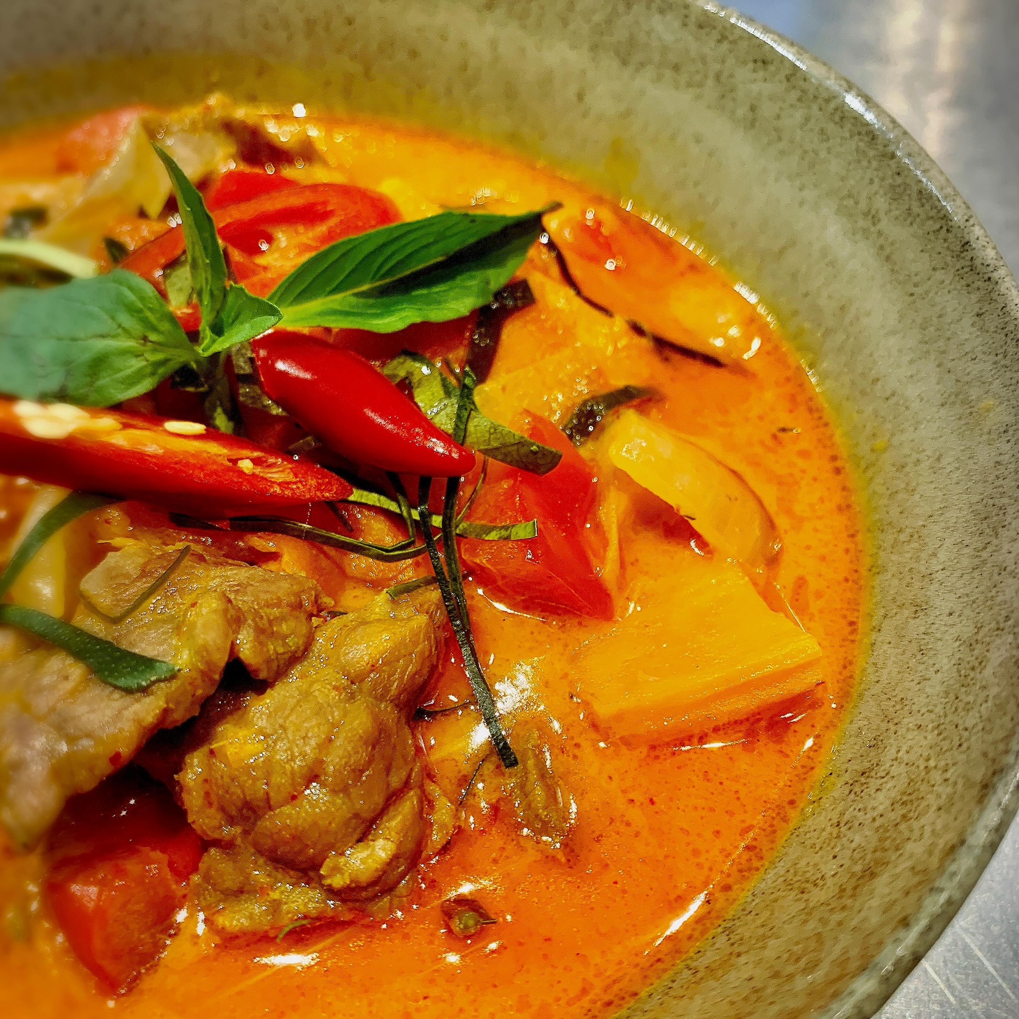 A bowl of red curry with meat, vegetables, and herbs at Aari Thai, a halal restaurant in Antwerpen, Belgium.