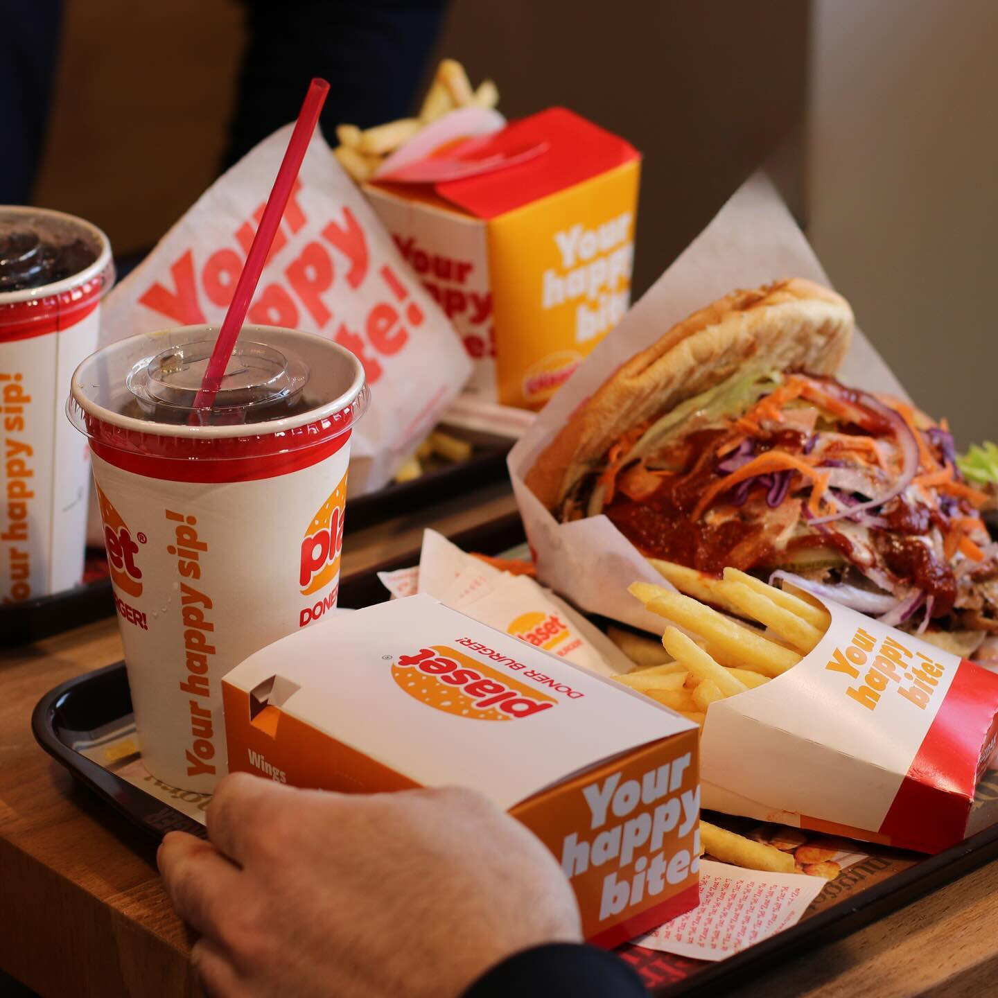 Un repas comprenant un burger, des frites et des boissons au Plaset Doner Burger, un restaurant halal à Ixelles, Belgique.