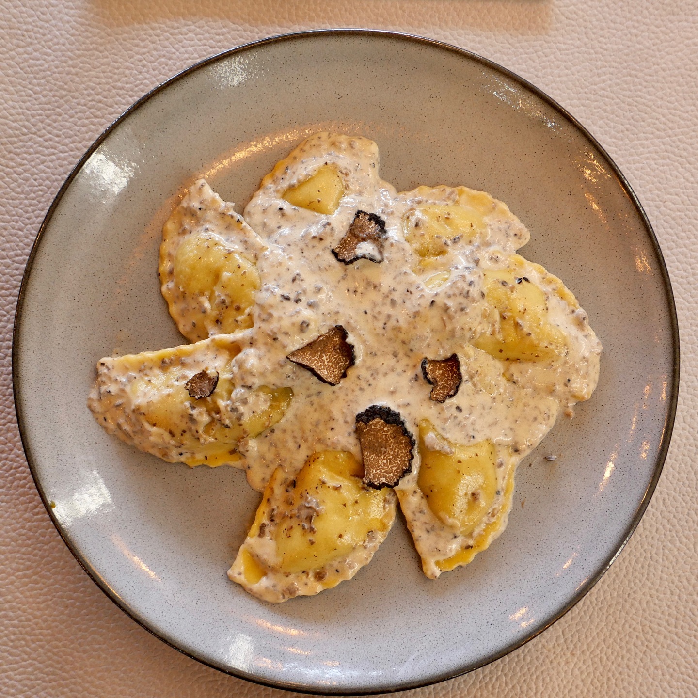 Een bord ravioli belegd met een romige saus en gegarneerd met truffelschijfjes in halal restaurant The Manzoni in Brussel, België.