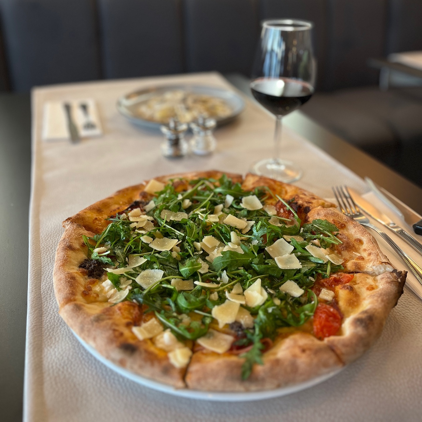Een pizza belegd met rucola en geschaafde Parmezaanse kaas in halal restaurant The Manzoni in Brussel, België.