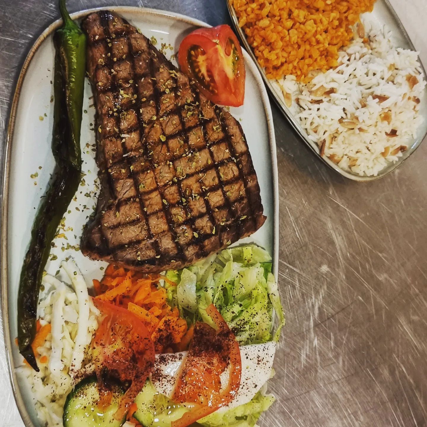 Un steak grillé avec des légumes, du riz et une salade d'accompagnement au restaurant halal The Cousins à Bruxelles, Belgique.
