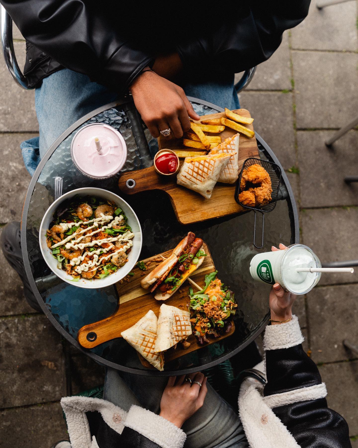 A variety of dishes including a salad, fries, and sandwiches at Taco's and burgers, a halal restaurant in Amsterdam, Netherlands.