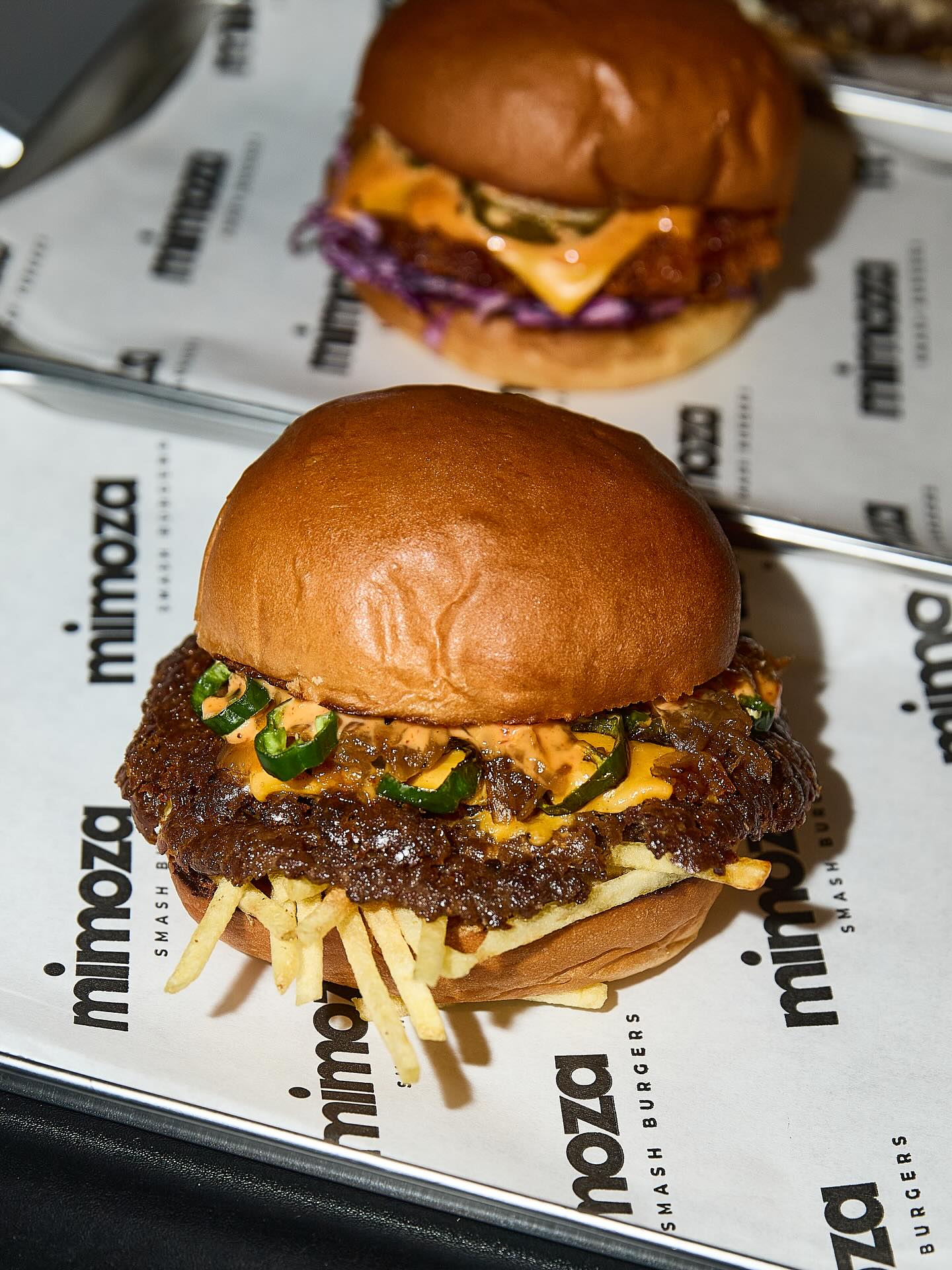 A burger with a beef patty, jalapeños, cheese, and fries at Mimoza Smashburgers, a halal restaurant in Rotterdam, Netherlands.