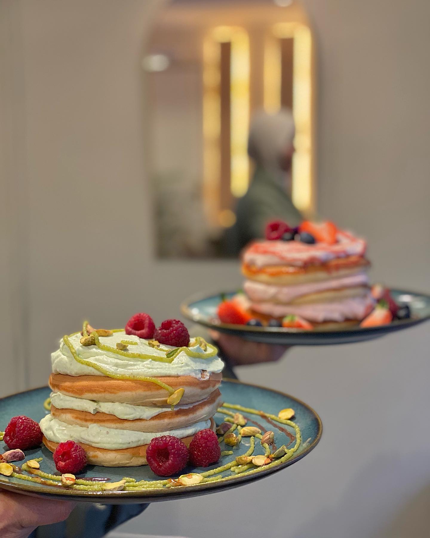 A stack of colorful pancakes topped with cream, raspberries, and pistachios at Riad, a halal restaurant in Molenbeek-Saint-Jean, Belgium.