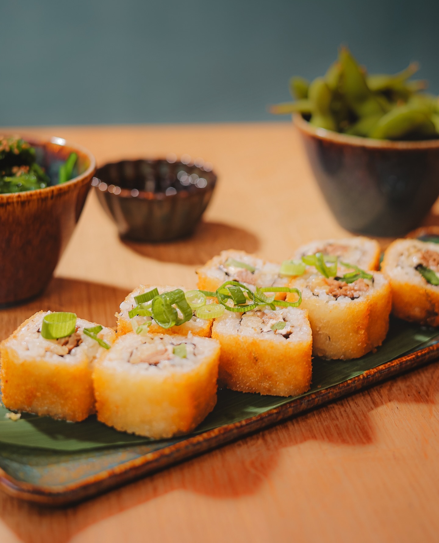 Een bord met krokante sushirollen, gegarneerd met groene uien, bij Tsuki, een halal restaurant in Anderlecht, België.