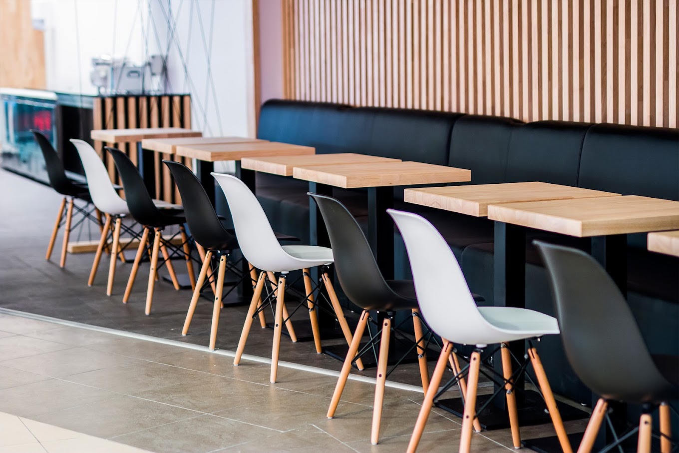 The interior of halal restaurant YouWok in Wijnegem, Belgium, showing wooden tables and black and white chairs arranged in a modern layout.