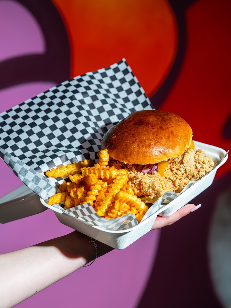 A crispy fried chicken sandwich with cheese and purple cabbage, served with crinkle-cut fries at Bad Bun, a halal restaurant in Ixelles, Belgium.