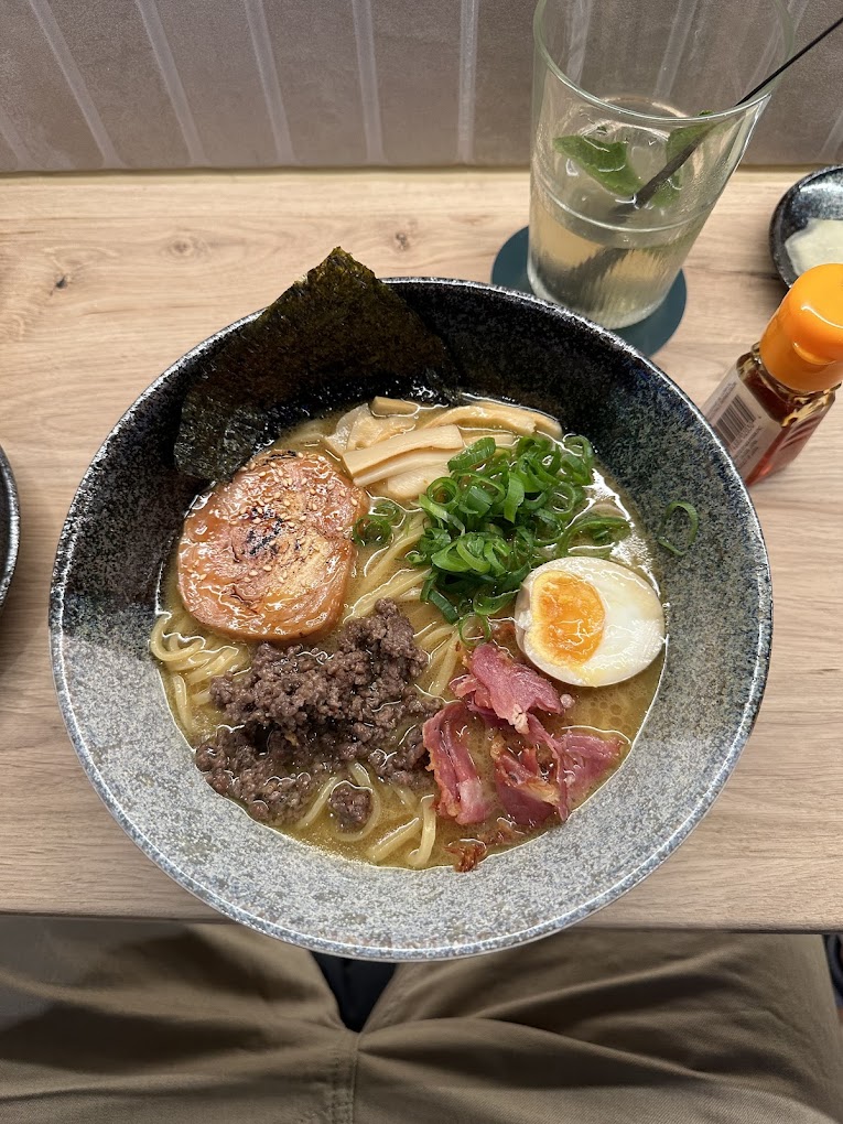 A bowl of ramen with various toppings including sliced pork, green onions, and a soft-boiled egg at Maruki, a halal restaurant in Rotterdam, Netherlands.