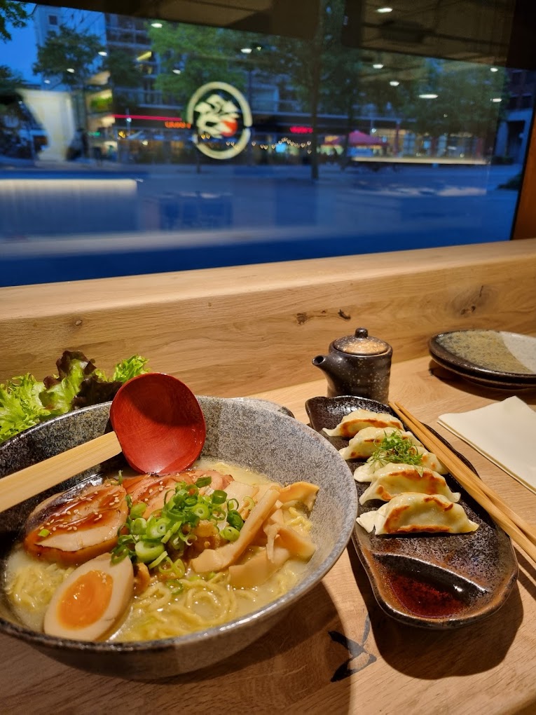A bowl of ramen with sliced pork, soft-boiled egg, green onions, and gyoza at Maruki, a halal restaurant in Rotterdam, Netherlands.