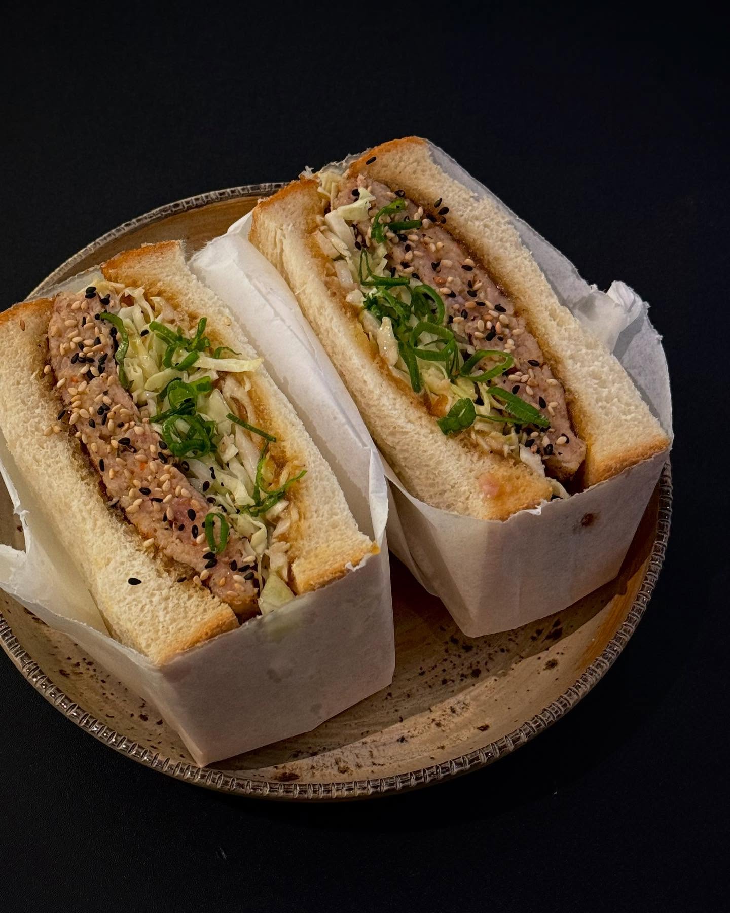 A sandwich filled with seasoned meat, cabbage, and green onions, topped with sesame seeds, at Bento Café, a halal restaurant in Rotterdam, Netherlands.