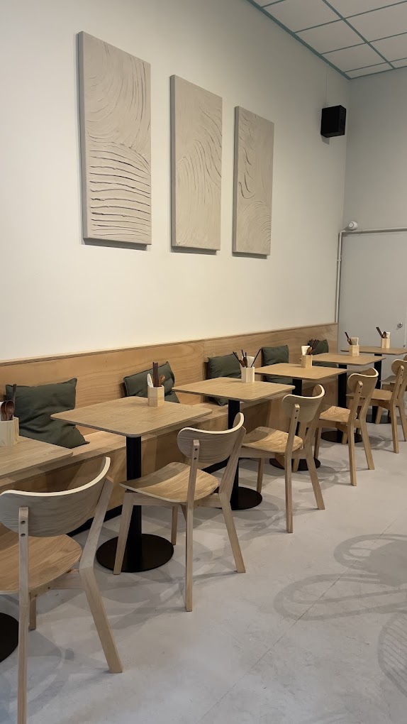 The interior of halal restaurant Bento Café in Rotterdam, Netherlands, showing wooden tables, chairs, and textured wall art.