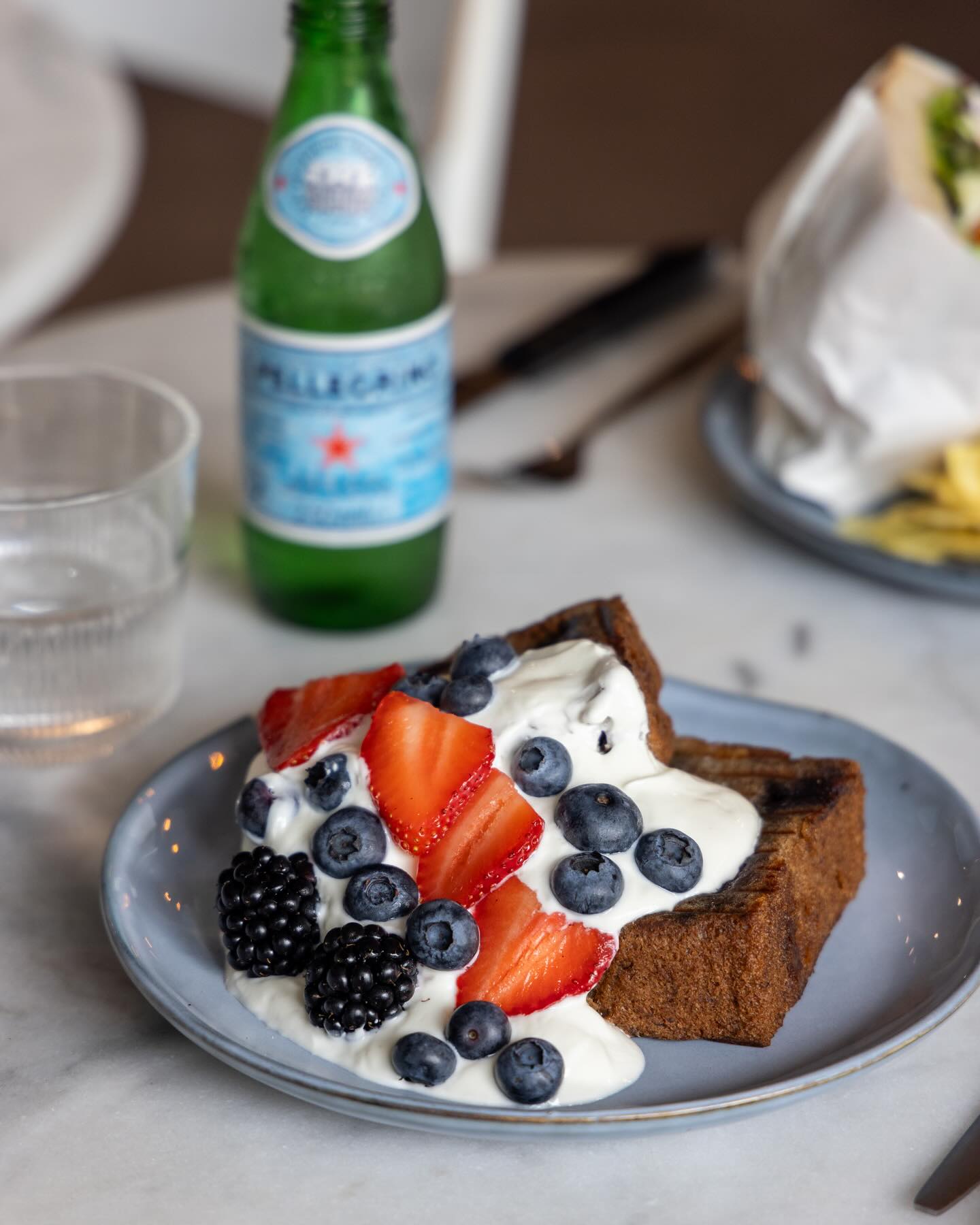 A slice of bread topped with yogurt and mixed berries, including strawberries, blueberries, and blackberries, at Koffie Met Tony, a halal restaurant in Ede, Netherlands.