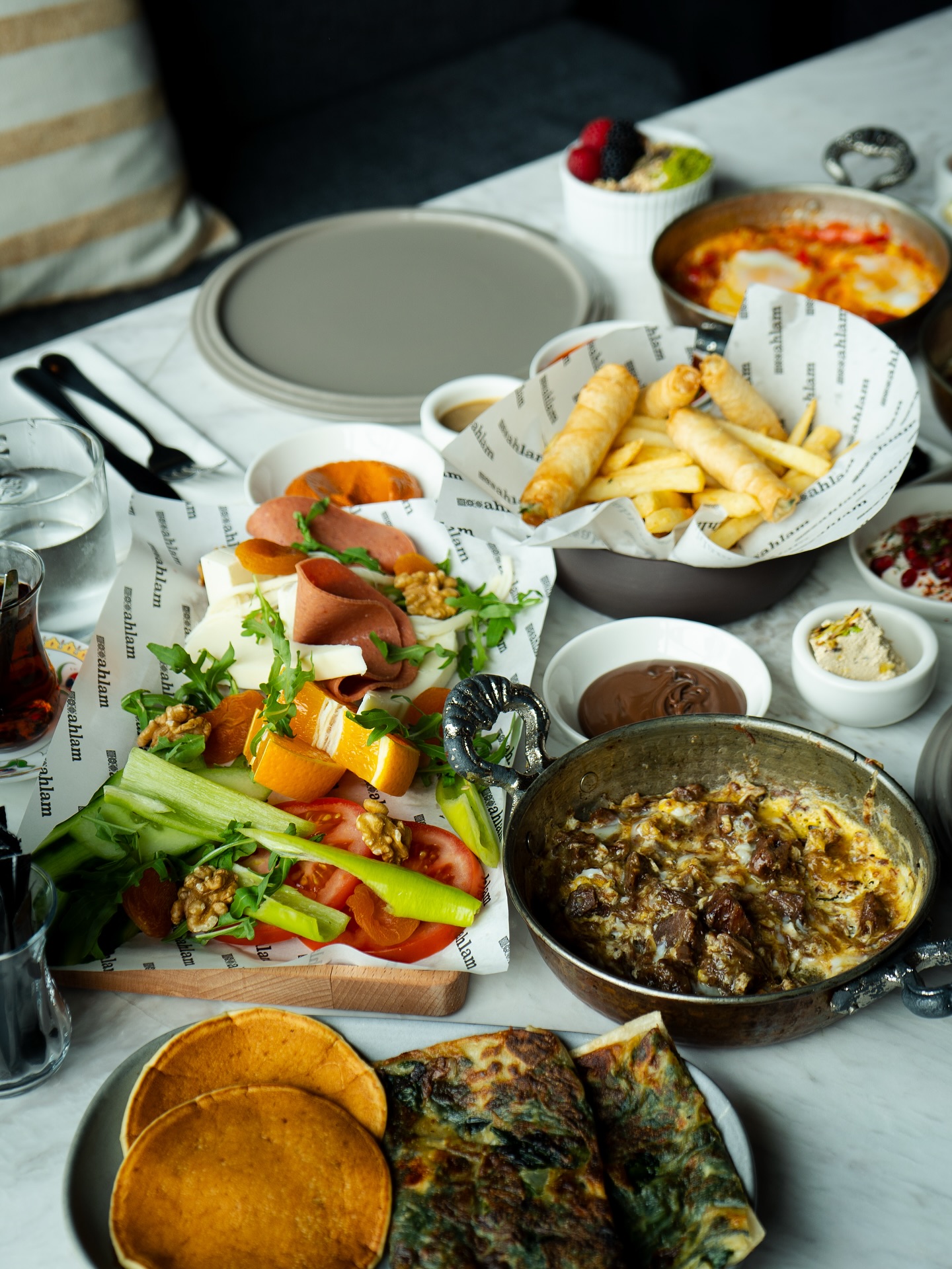 A variety of dishes including fresh vegetables, meats, and pastries at Restaurant Ahlam, a halal restaurant in Den Haag, Netherlands.