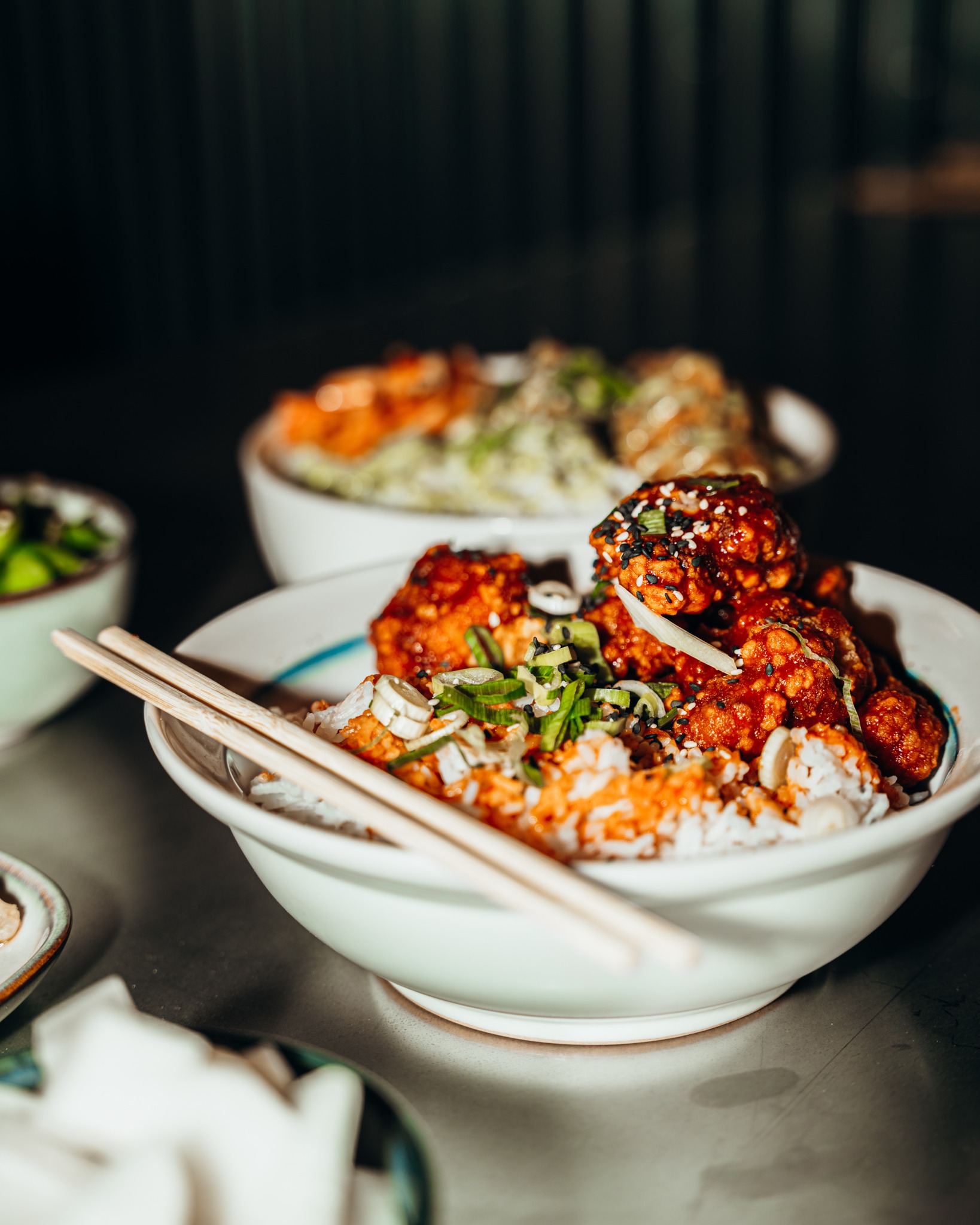 A bowl of rice topped with spicy fried chicken, garnished with green onions and sesame seeds at Seoul South Station, a halal restaurant in Gent, Belgium.